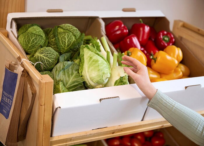Vegetable shelf in the supermarket, vegetables are stored in white corrugated cardboard boxes